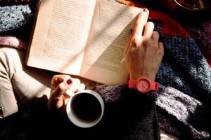 person reading a book holding coffee