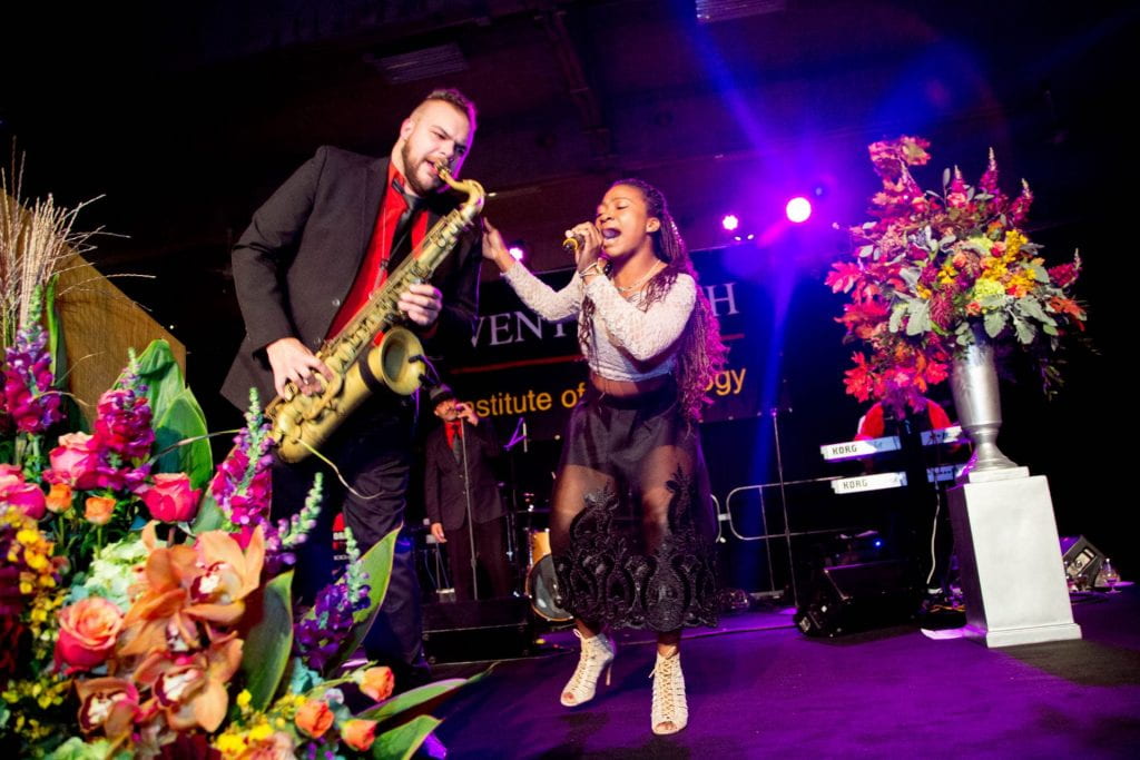 man playing saxophone and woman signing on stage