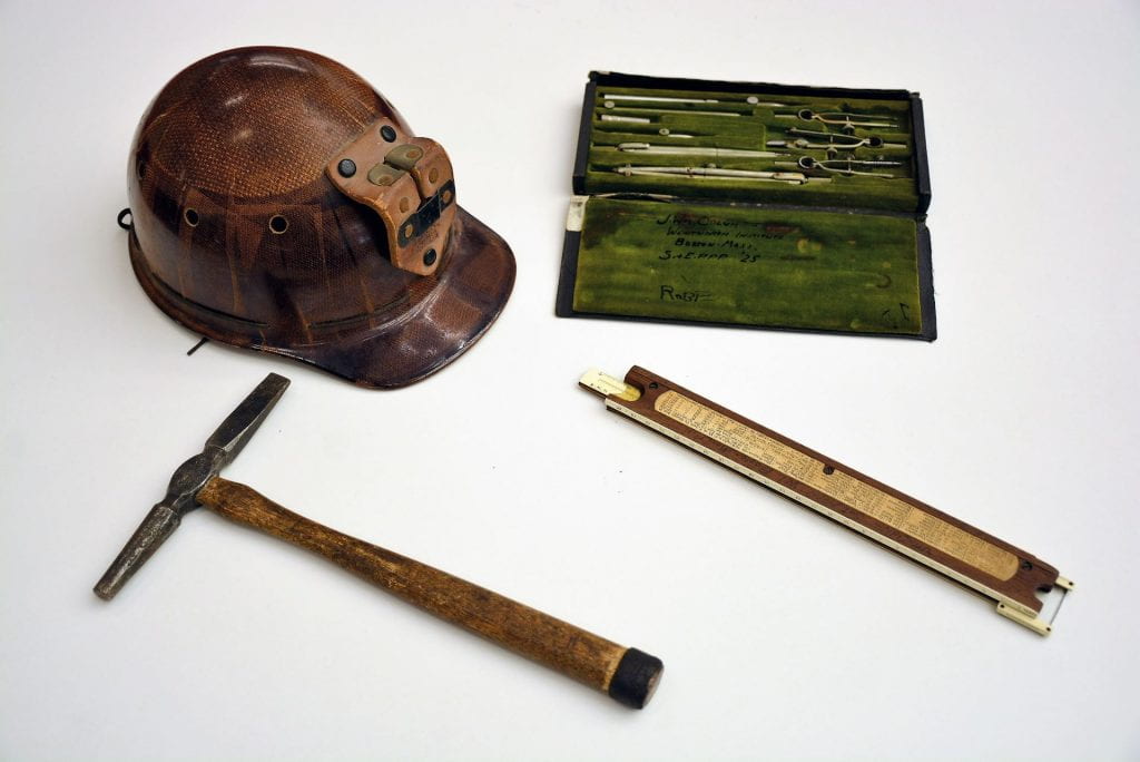 helmet, slide ruler, and hammer laid out on a table